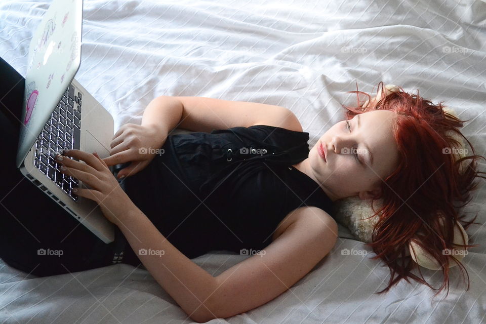 Girl using a laptop in bed