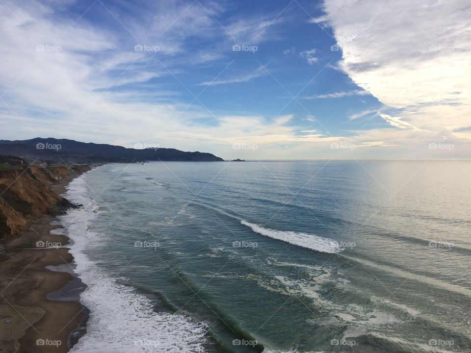 Pacific Ocean, Pacifica CA. The waves of the Pacific Ocean slowly erode the sandy cliffs along the shore in San Mateo County, California. 