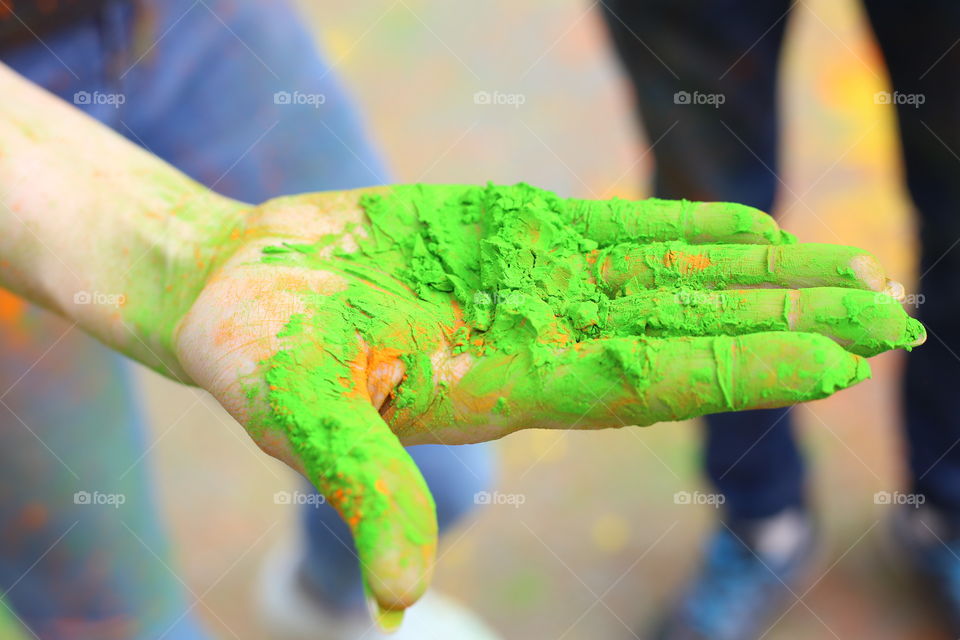 Woman's hand in green holi paint close up. Holi festival concept