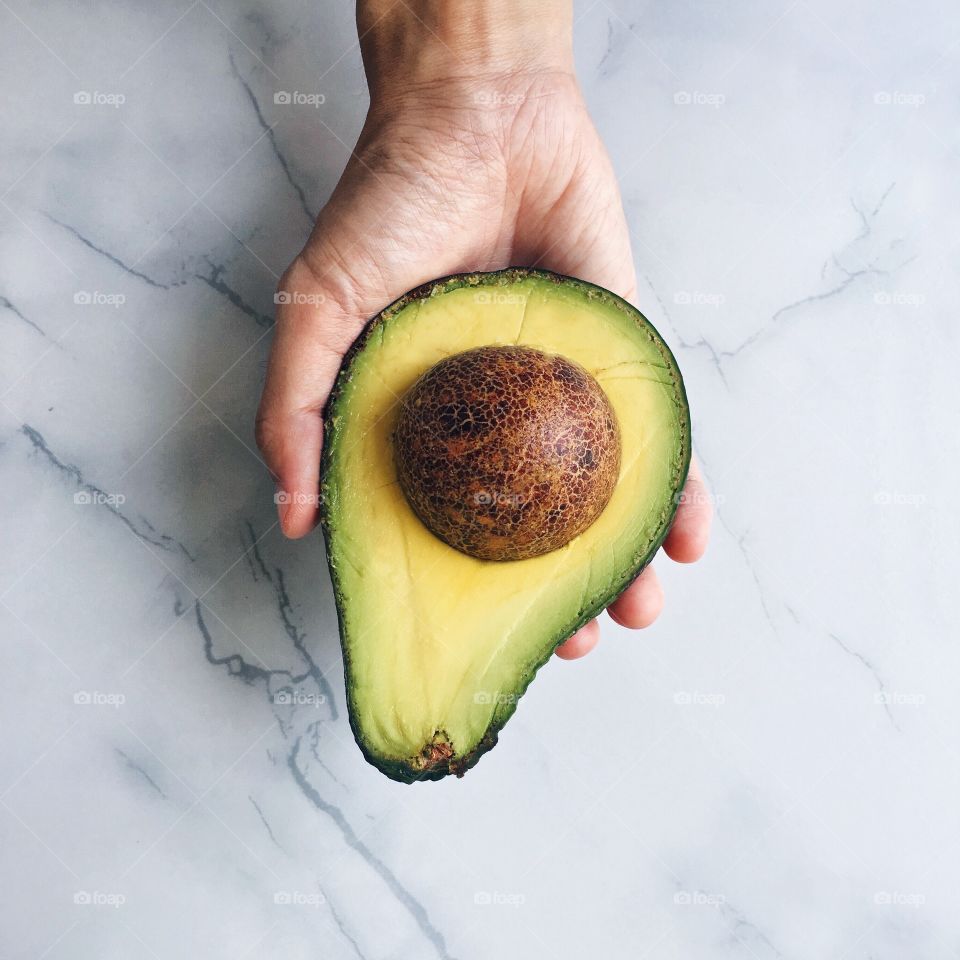 Half avocado in hand