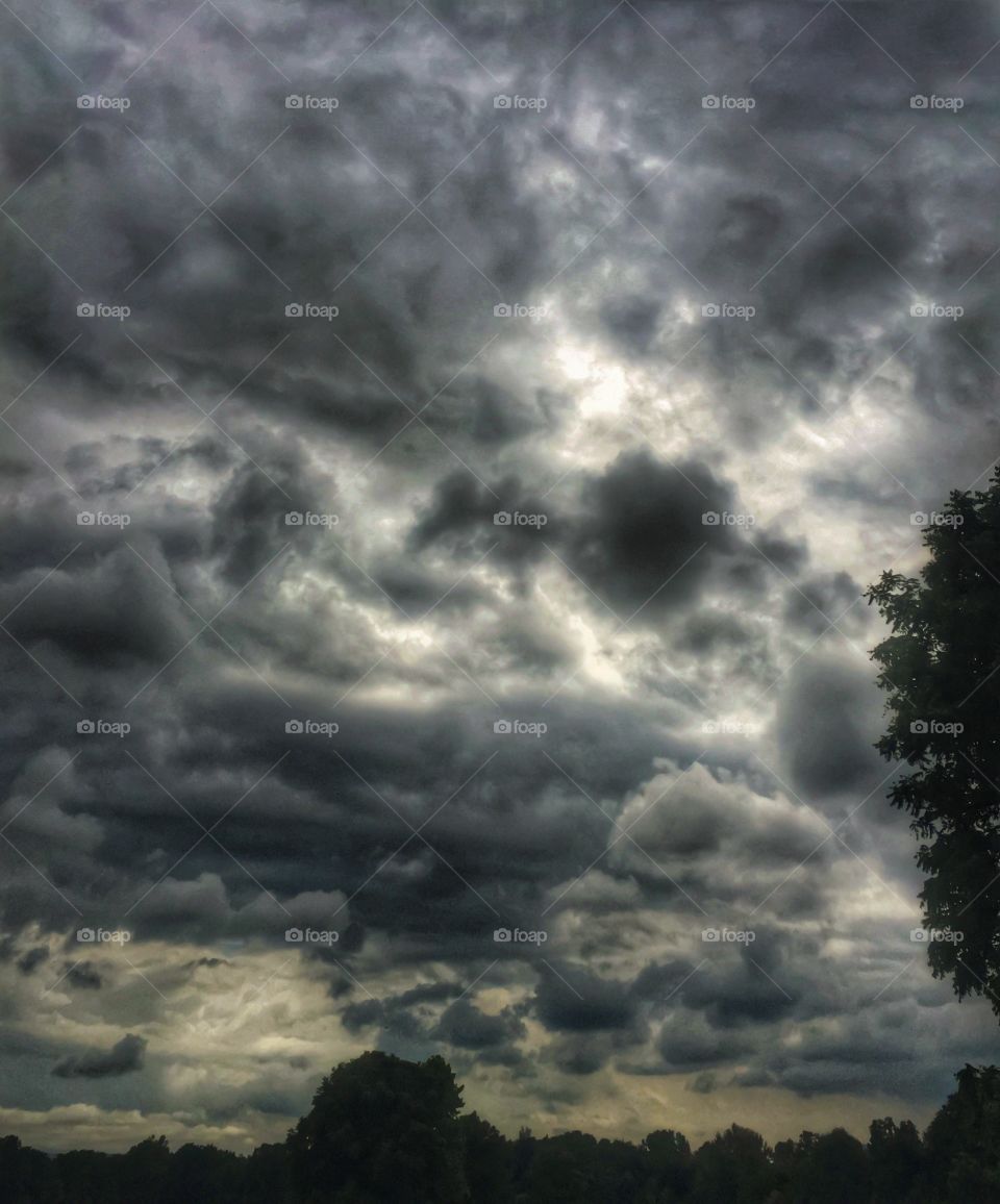 Looking up an ominous clouds. . Ominous clouds layer themselves in the sky. 