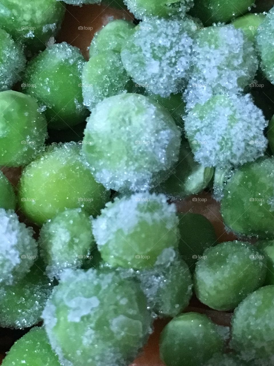 Close up view of the ice crystals on green frozen peas in the kitchen before cooking 