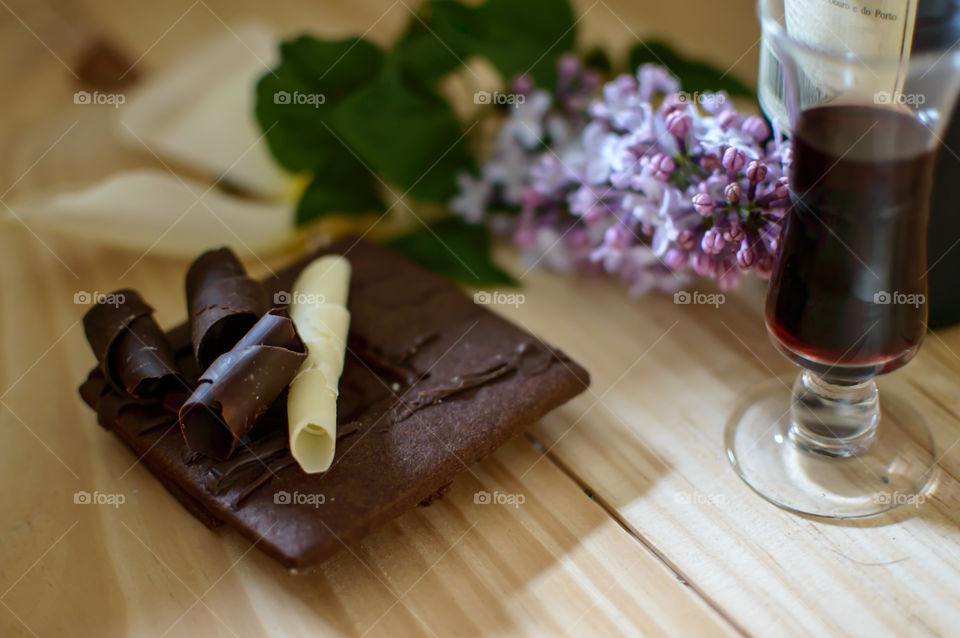 Low angle view of dark chocolate and white chocolate on shortbread cocoa cookie on wood background with vintage Porto wine and fresh flowers conceptual wine tasting and pairing gourmet food photography 