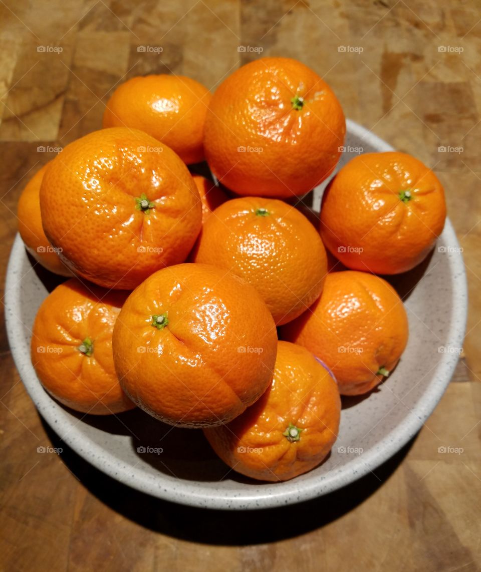Tangerines in bowl on oak chopping block.