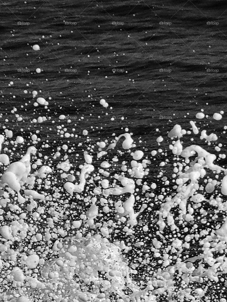 Sea foam rises up to the camera lens.