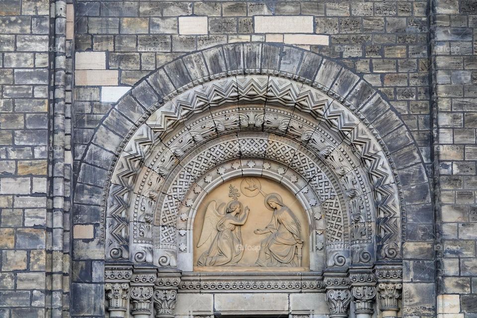 Relief with the Virgin Mary and the angel. Neo-romanesque portal of old Saint Cyril and Methodius Church from the 19th century in Karlin, Prague, Czech Republic.