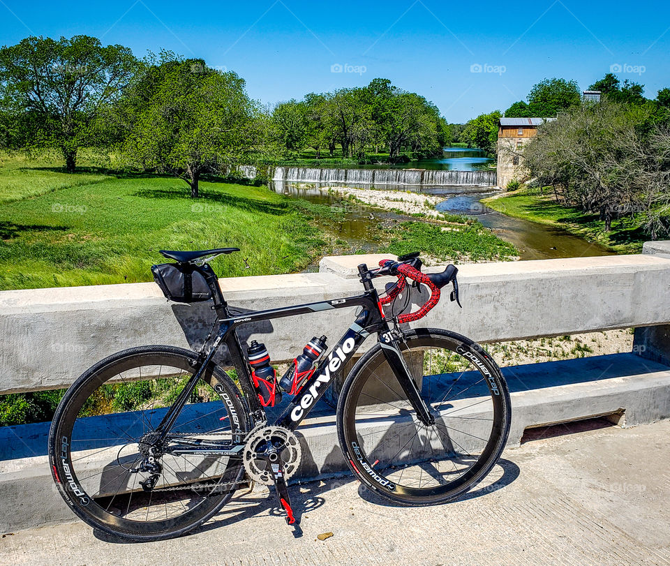 A cyclist takes a break along a rural route at a river crossing at an old mill