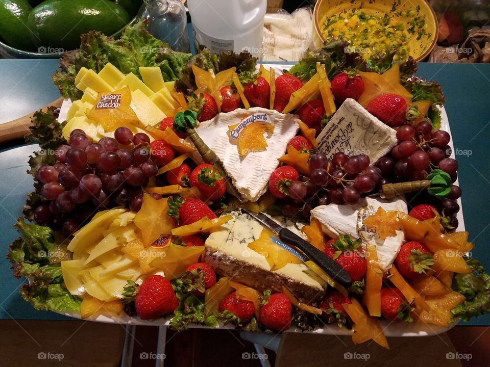 cheese plate with different cheeses and fresh fruit, grapes and berries