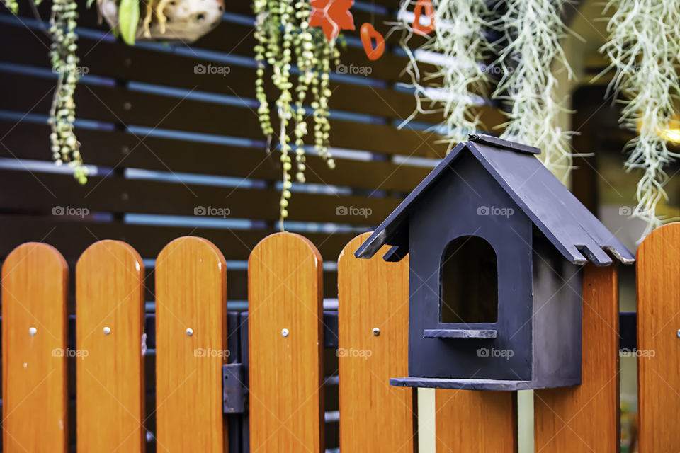 The wooden mail box is a small house.