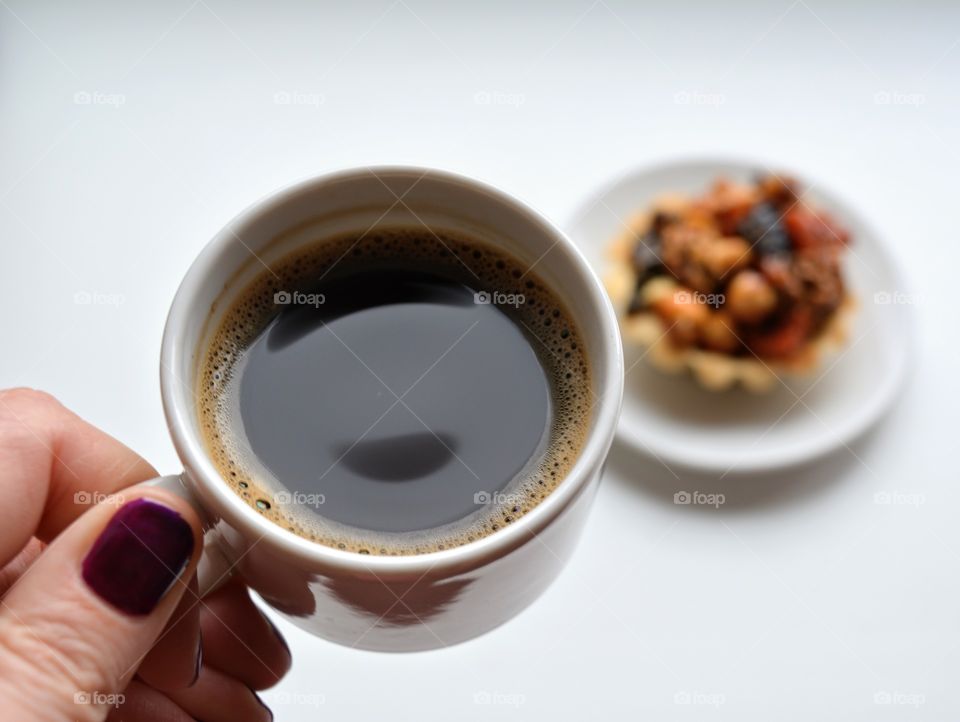 coffee mug in female hand and cake on a white background