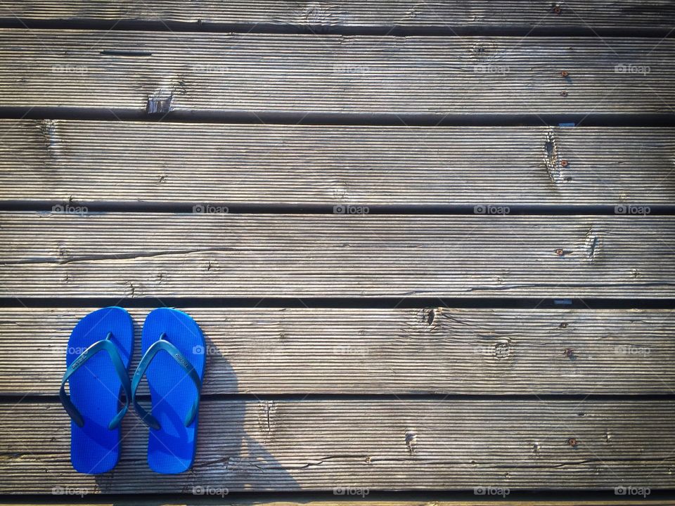 Minimalistic view of blue flip flops in the corner of a wooden pontoon