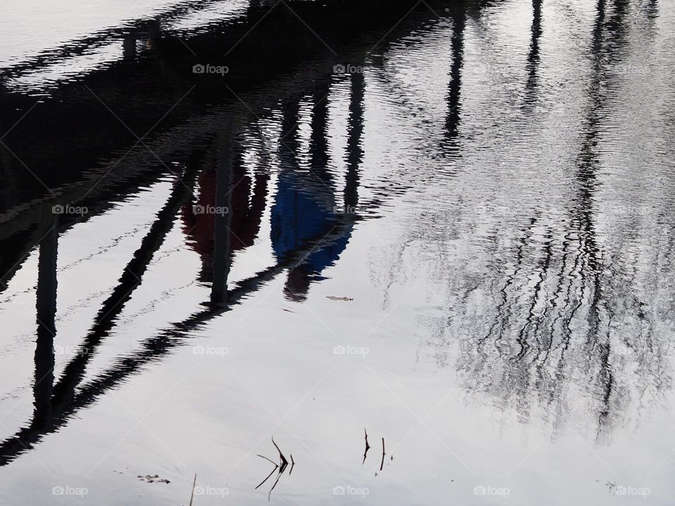 Shadows/reflections in the water from man walking on a bridge