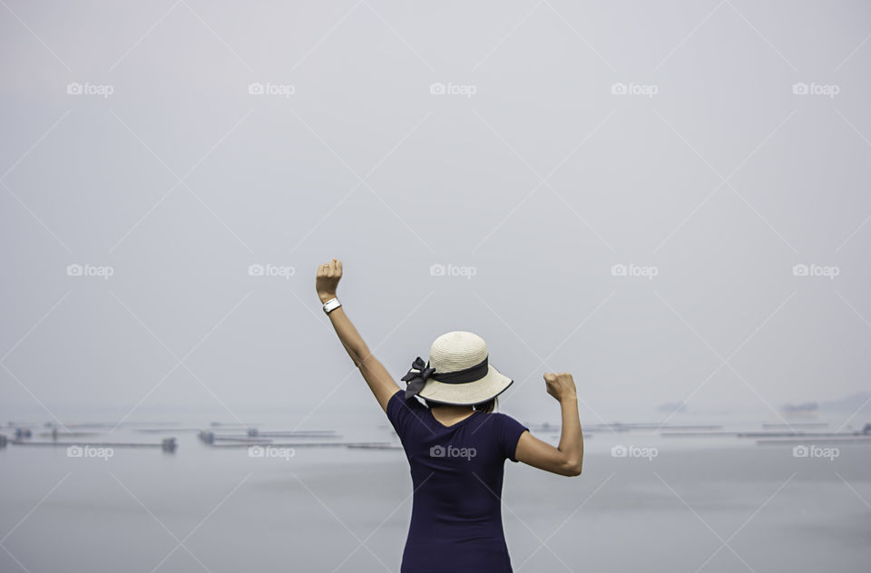 Women raise their arms Background The raft floating fish farming at Krasiew dam ,Supanburi Thailand.