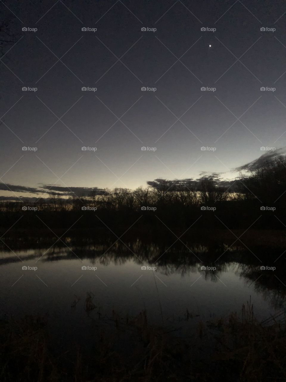 A calm evening cloudscape over the still water and forest.