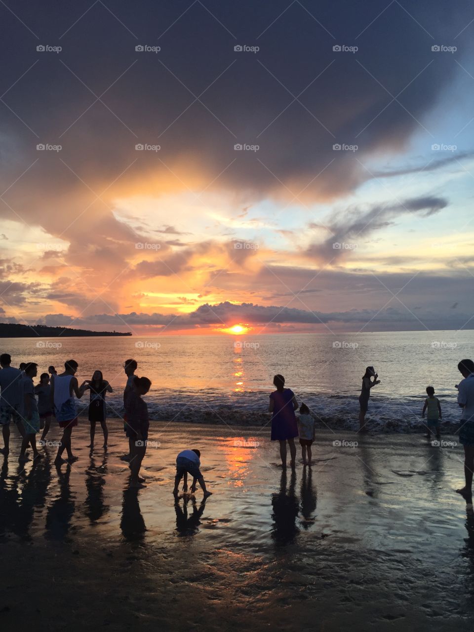 People gathered to watch the sunset by the beach with low tide. 
