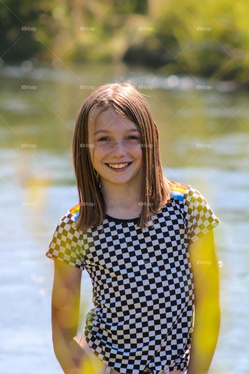 Smiling daughter along the lake in Southern Oregon, with a black and white checkered shirt