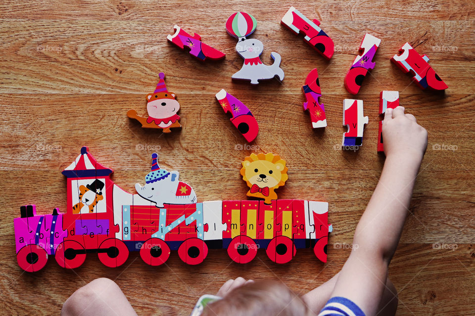 Child putting together a wooden alphabet train puzzle