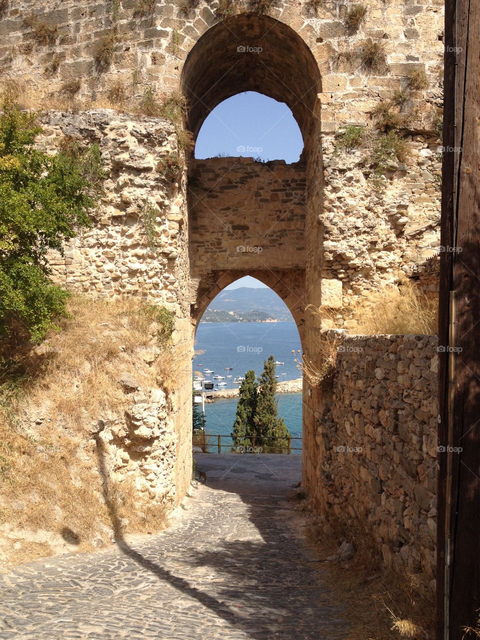 Arched doorway of an old castle in Koroni, Greece overlooking the beautiful blue sea below 