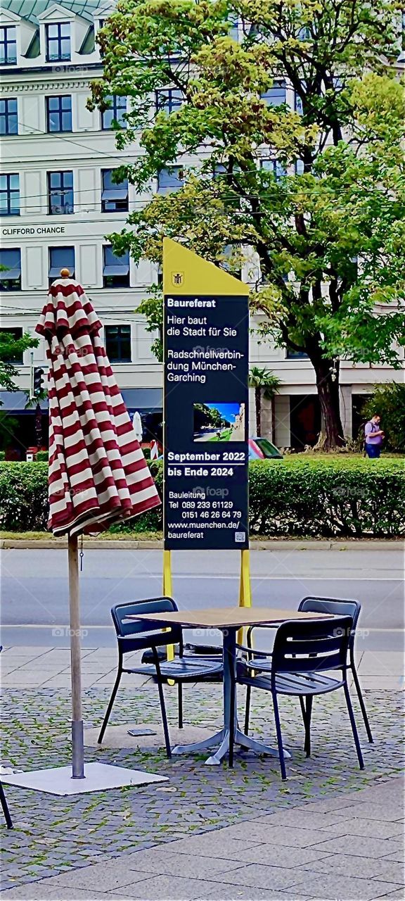 A striped umbrella adorns the sidewalk near the „Lenbachhaus“ in the „Luisenstraße“ in „Munich“, „Bavaria“, Germany, a popular art museum. This is actually a high speed bicycle lane according to the sign. 2023. Hypnotic Productions