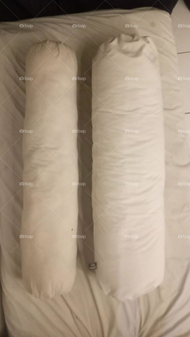 two bolster pillows with different sizes but the same color