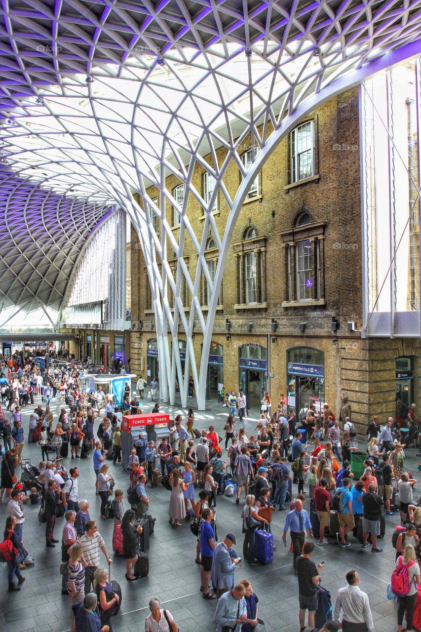 The main concourse and lattice roof of King's Cross train station during peak time or rush hour and packed with commuters and passengers.