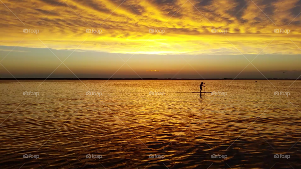 Board'n On The Bay. Stand up Paddle Boarder strides across the bay during a perfect summer sunset down the shore.
