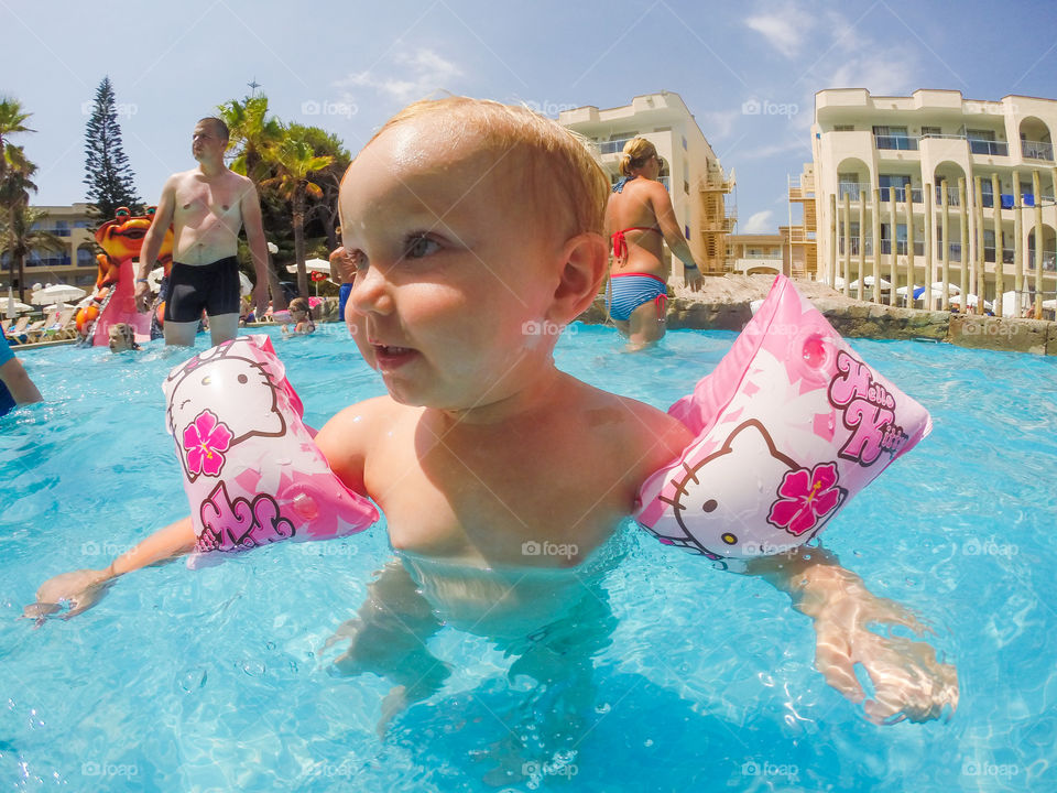 Two year old girl playing in the pool at AlcudiaPins on Majorca on her holiday.