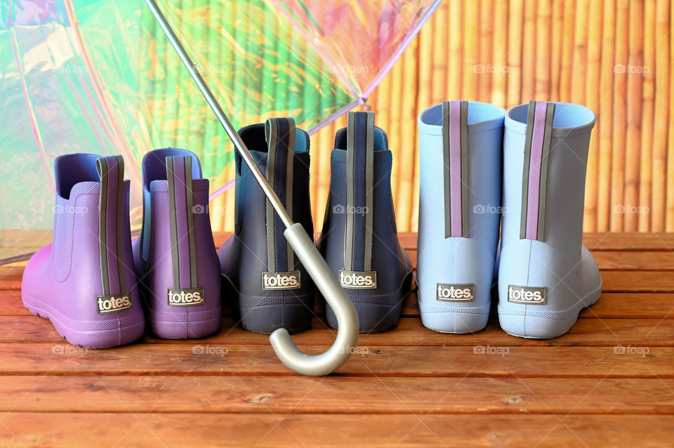 Colorful boots under the transparent umbrella 