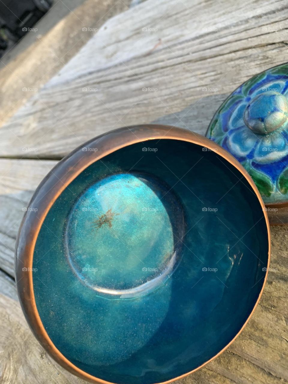 A handmade hammered copper bowl with a beautiful blue and green lid, for storage. 