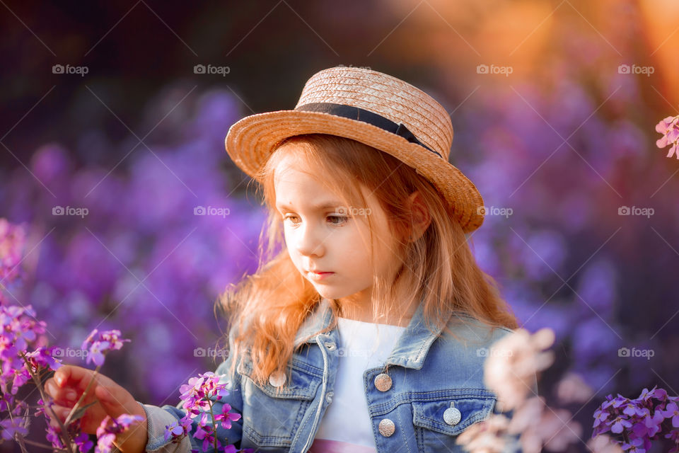 Cute little girl portrait in blossom meadow at sunset 