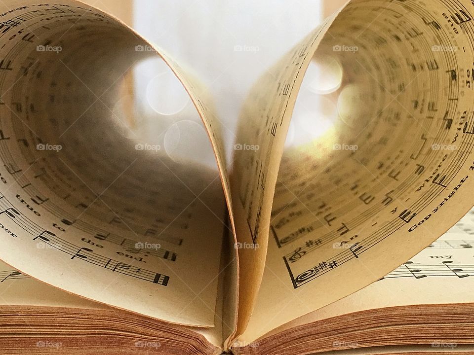 Old hymnal book open with pages in shape of heart