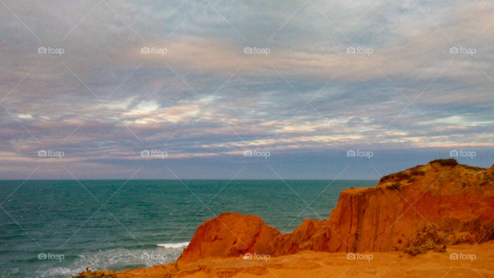 Cliffs of Morro Branco Beach in Brazil. The meeting of the sea with the Cliff.