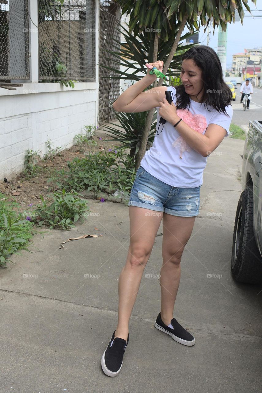 Young woman showing muscles in an avenue in the street