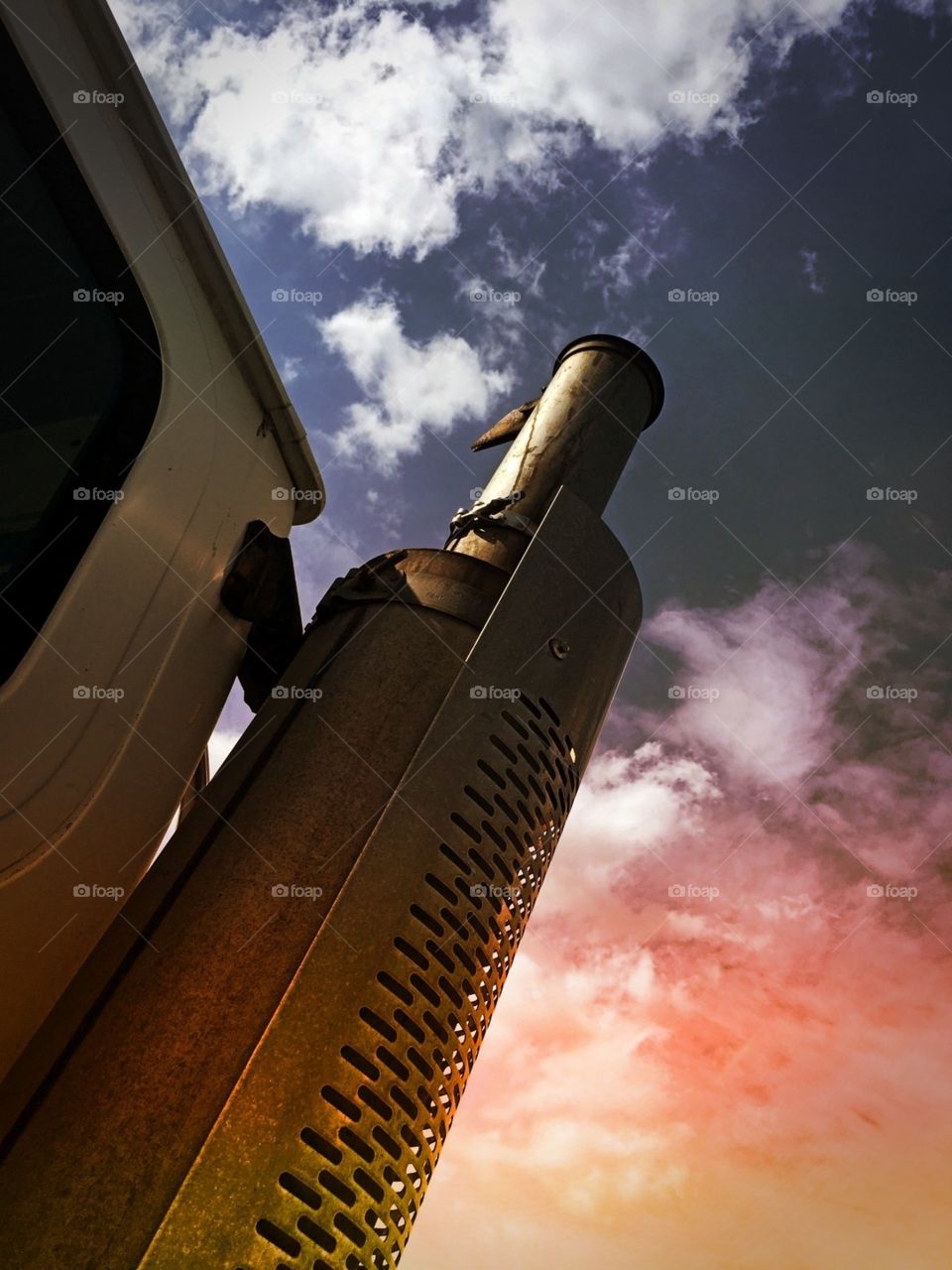 Dramatic sky by a smoke stack on a tractor trailer 