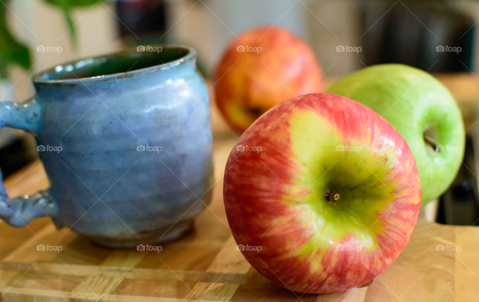 Red and Green Apples on wood in kitchen with artisanal mug still life healthy food and diet conceptual photography 