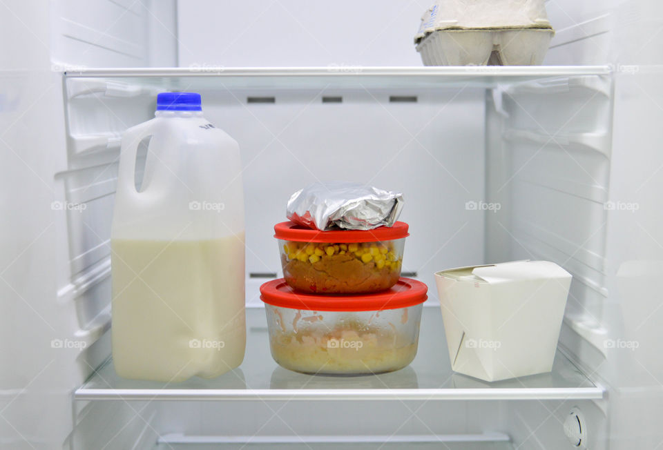 Leftovers and milk on the shelf of a refrigerator