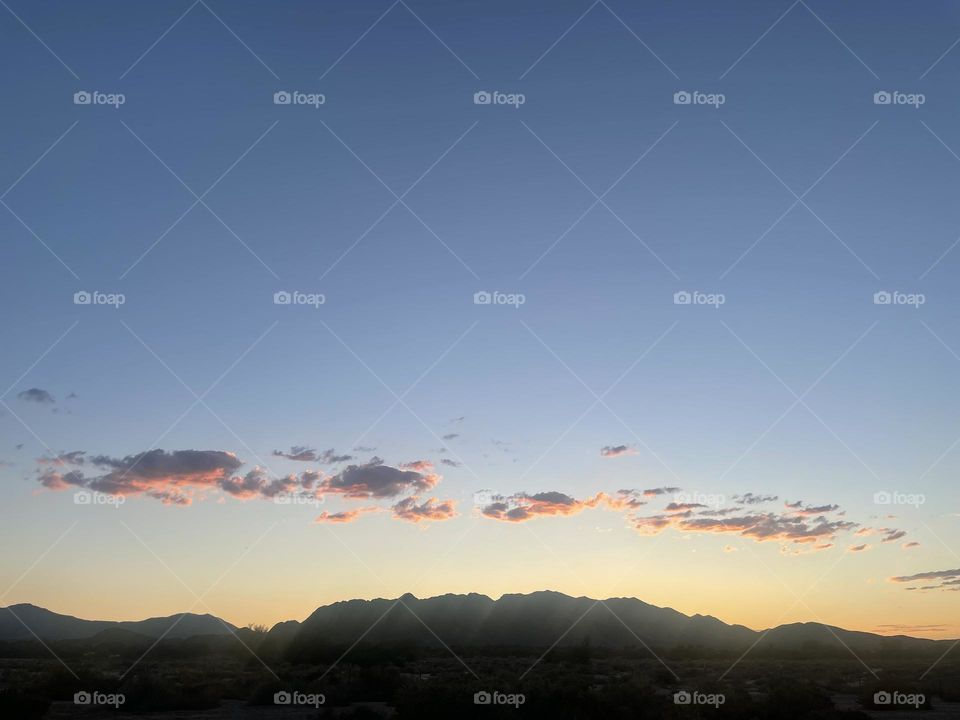 A colorful sunset with mountains and pink clouds. 