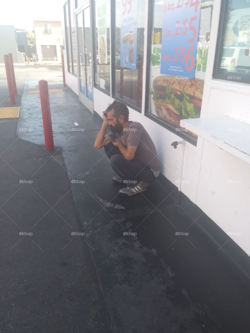 Homeless man at gas station deep in his thoughts