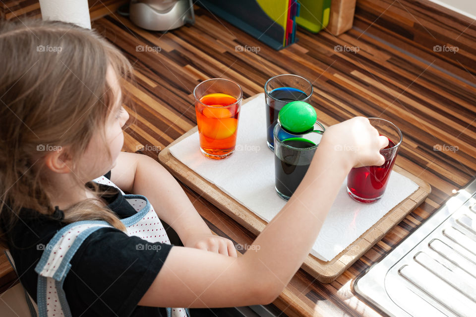 Little girl dyes Easter eggs in various colorants.