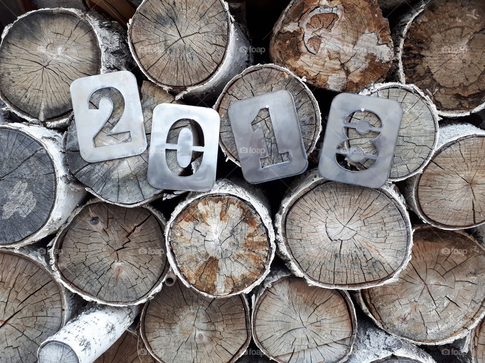 Inscription 2018 roughly cut out in separate figures from metal on the background of birch.