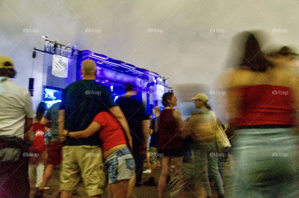 Crowds of people enjoying an evening outdoor music festival.