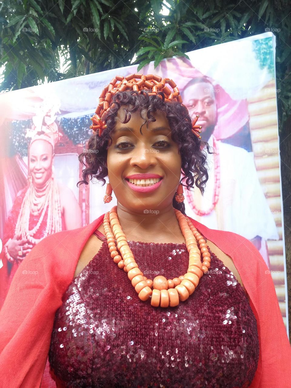 Edo lady in native Edo colours and coral beads wearing a burgundy dressy jump suit with a red pashmina