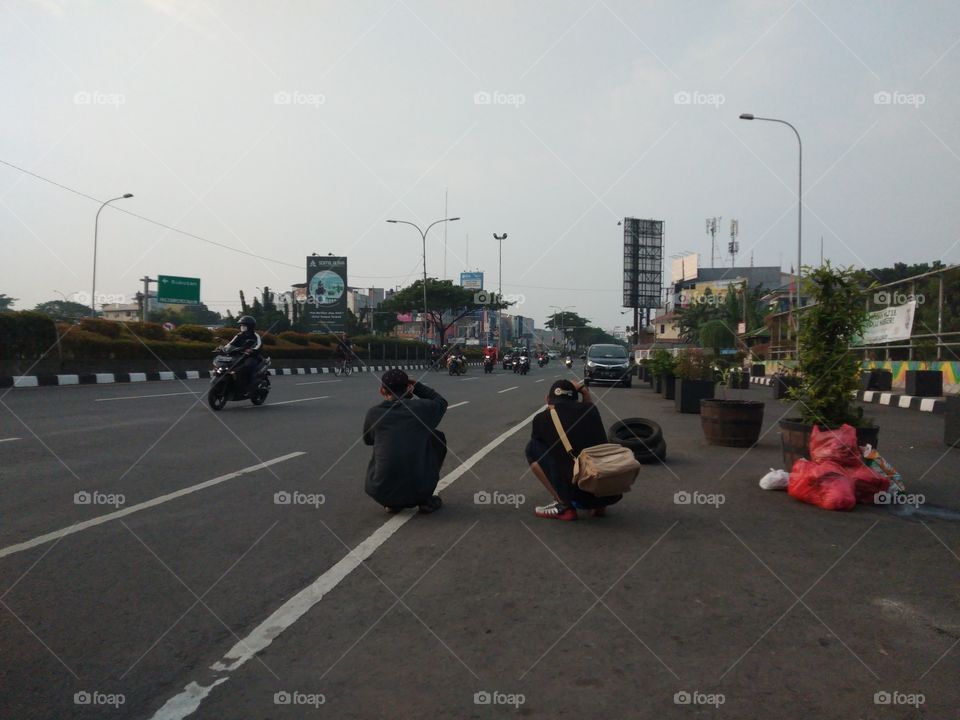 two photographers are seriously taking pictures of cyclists on the side of the highway