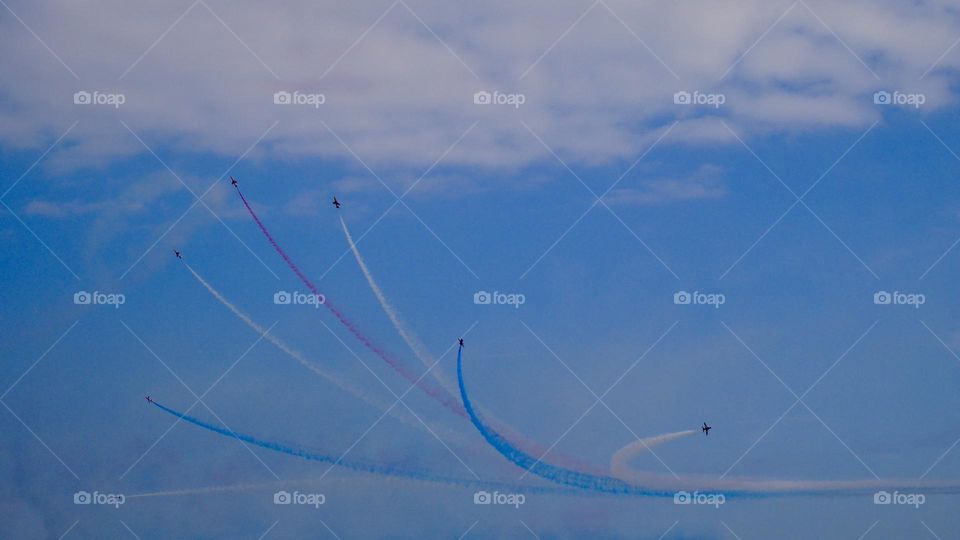 Acrobatic jet planes with United Kingdom flag colours fog during air show 