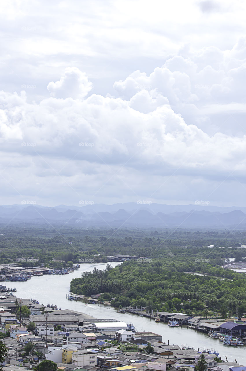 The point of view of Cityscape and a boat parked in Tha Taphao river , Background mountains and sky at Mutsea Mountain Viewpoint in Chumphon , Thailand.