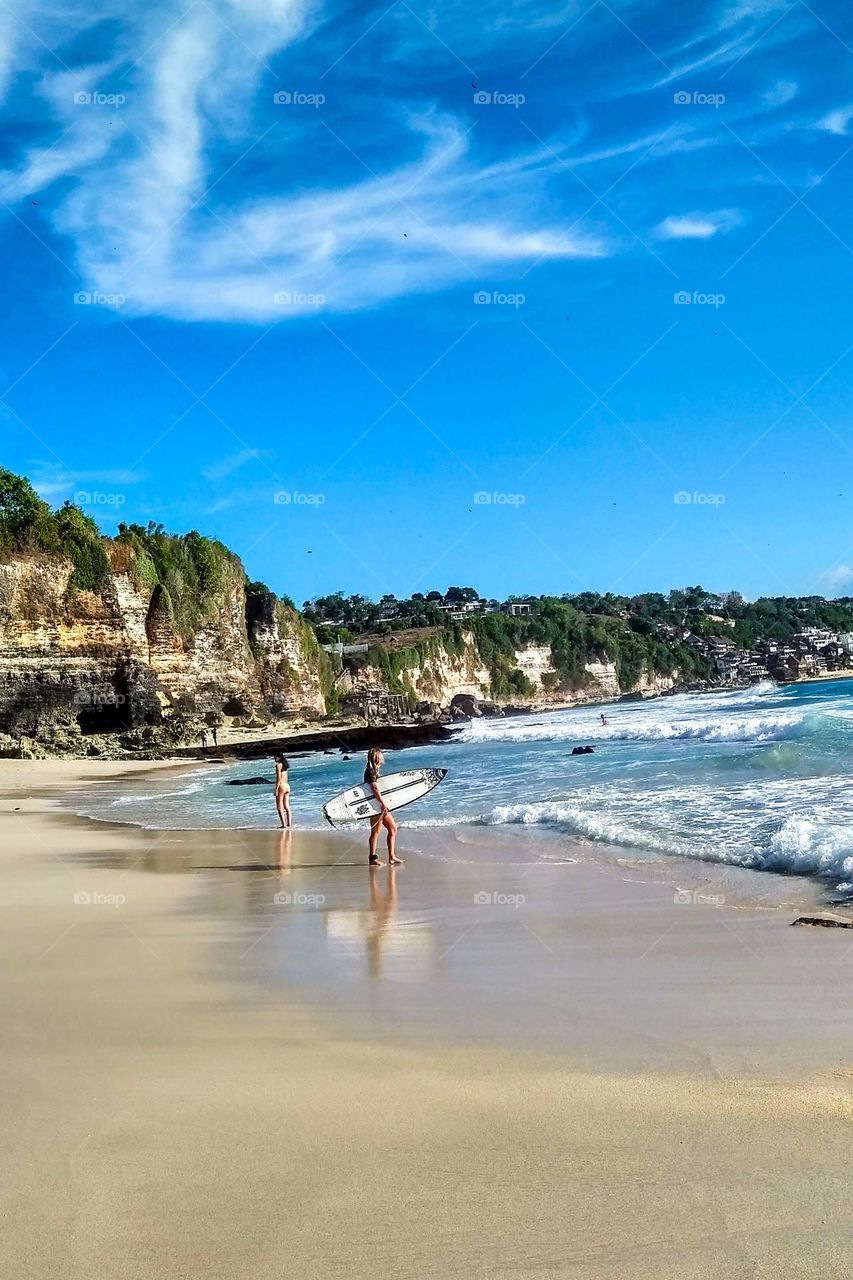 Hilly beach with people going surfing in eye level view