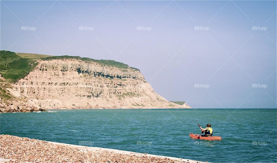 A canonist paddles around the coastline near Fairlight, UK 