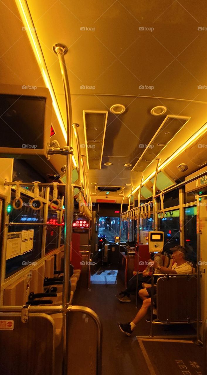 A retro-style bus with a warm yellow light interior. The marquee reads "Please pay attention to safety while driving" in Chinese