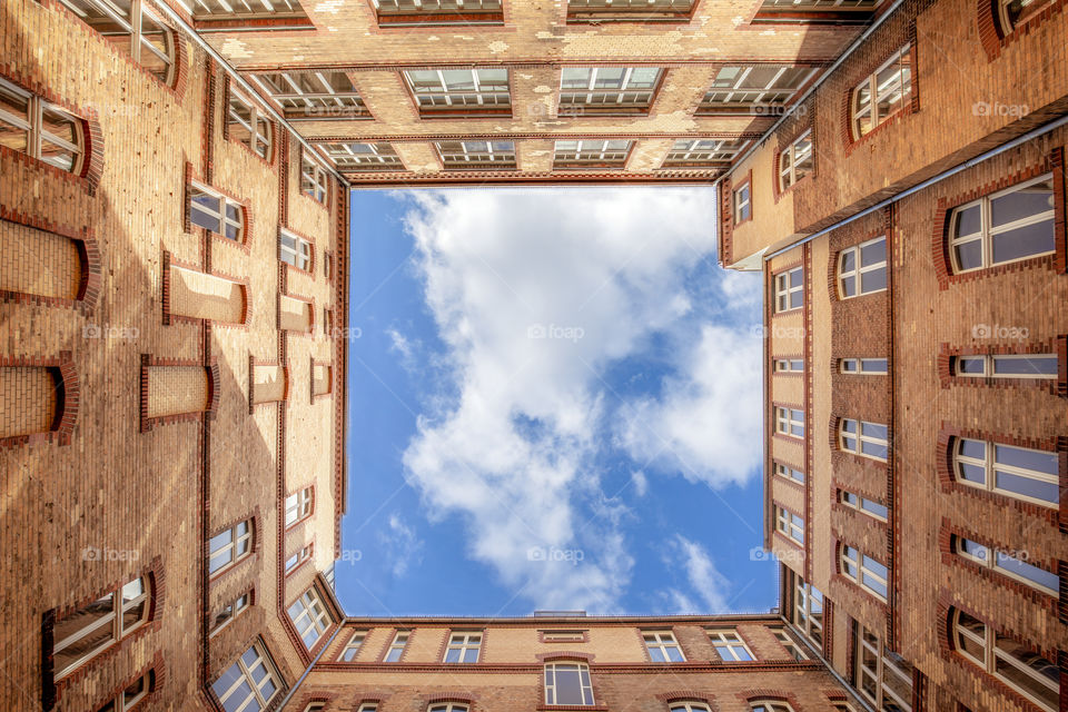 Architectural up view of the inner court of a building and the cloudy sky. Exterior walls with windows.