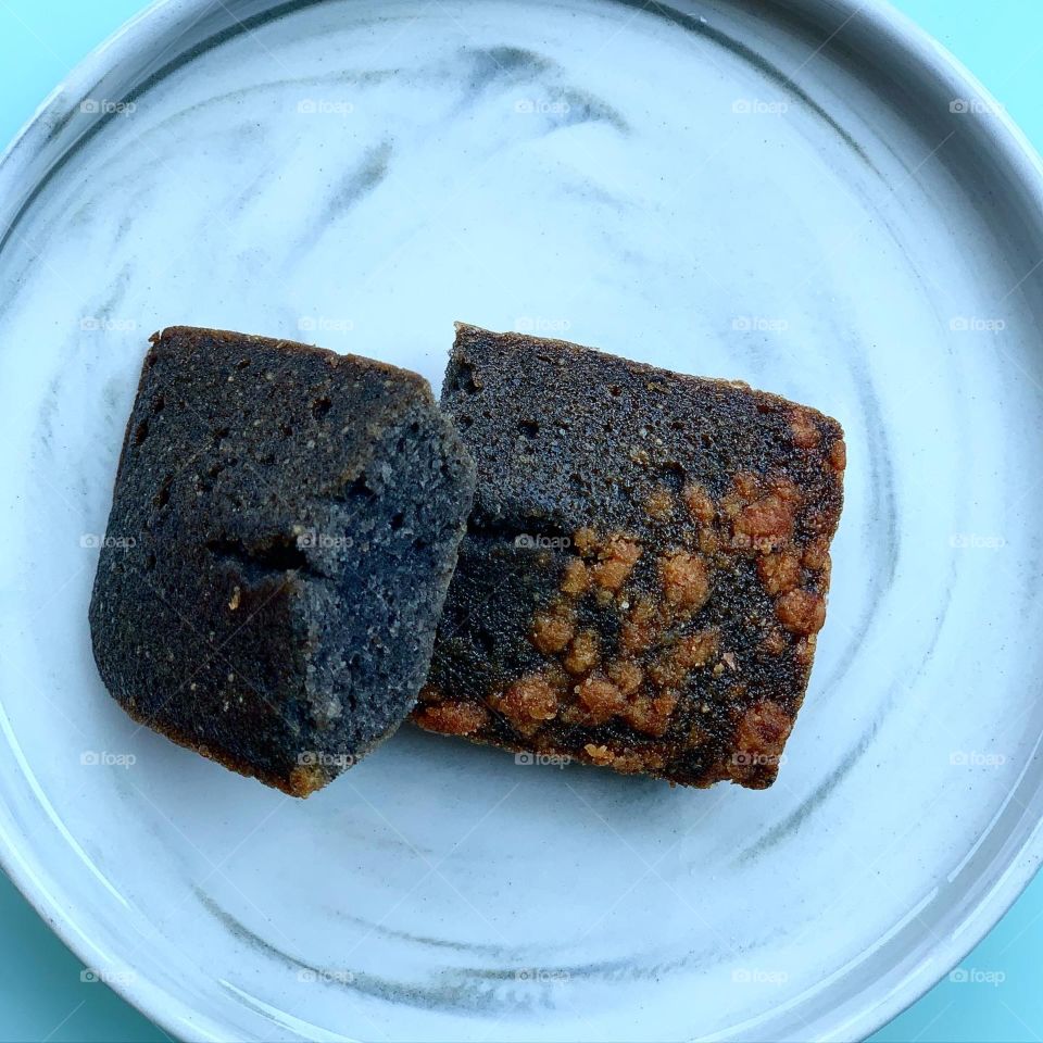 French patisserie financiers in four different flavours - brown butter, dark chocolate, black sesame and yuzu against a natural background  